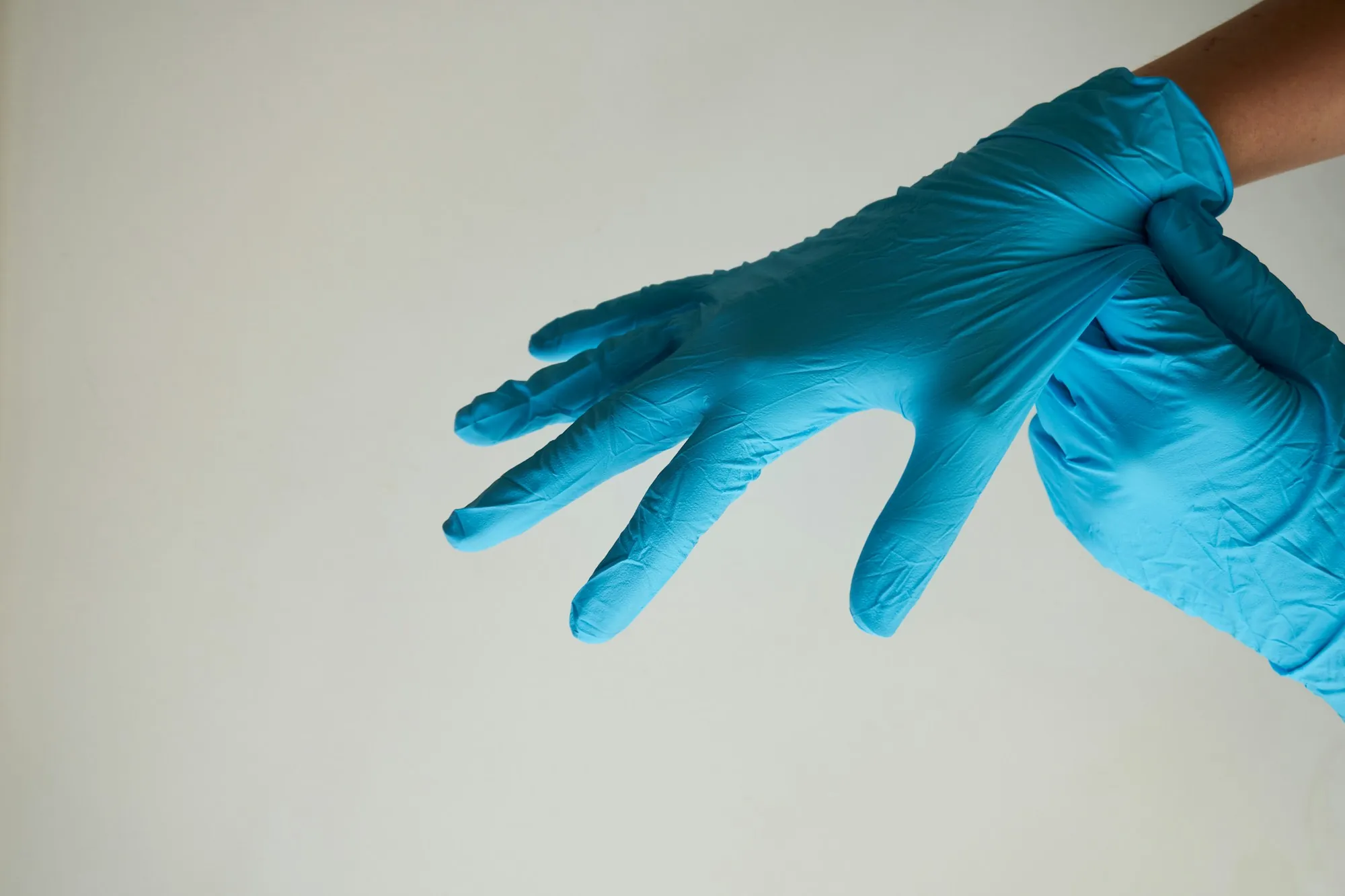 Hands pulling on teal cleaning gloves