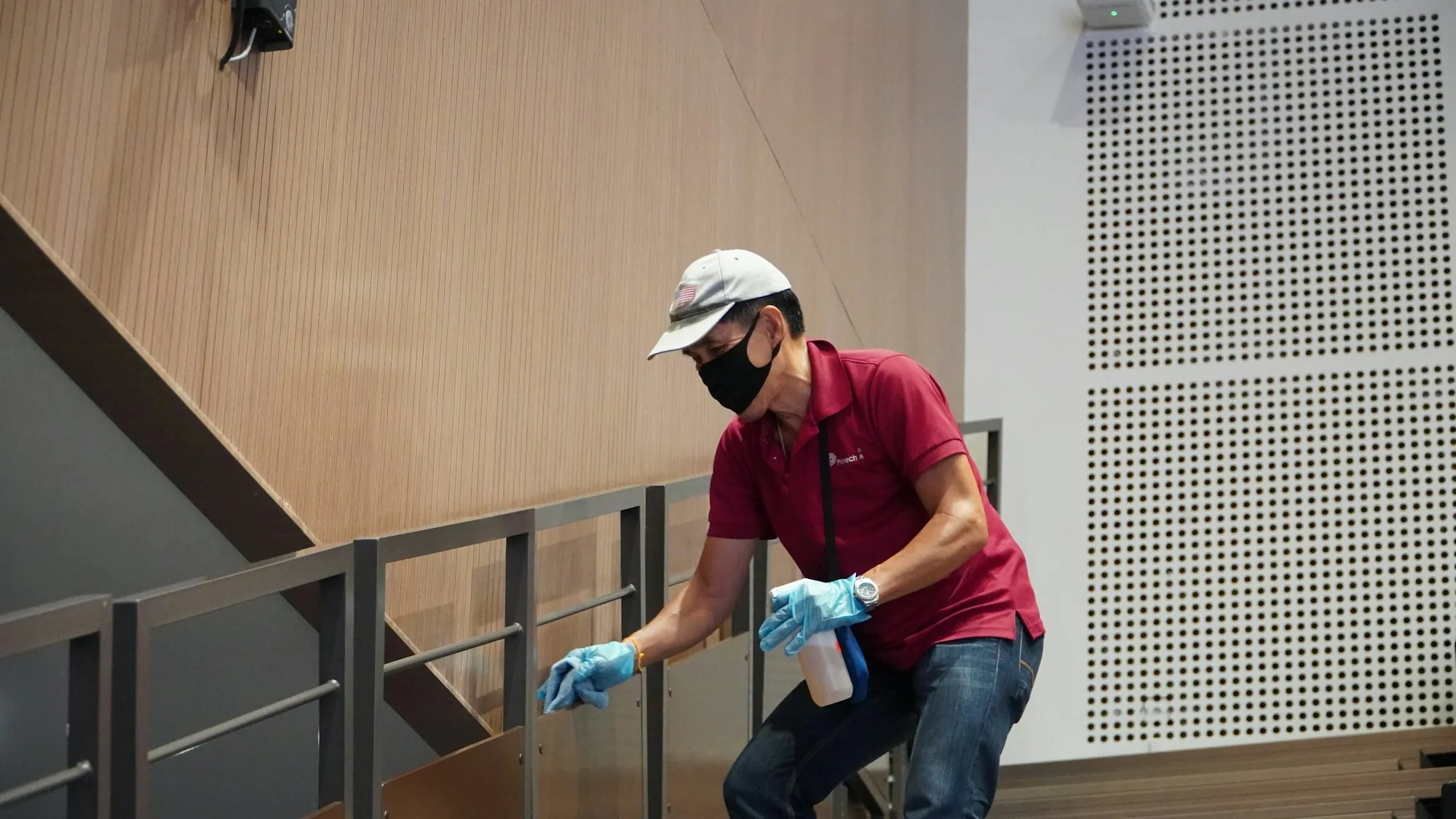 Worker in a mask and gloves wiping a stair railing